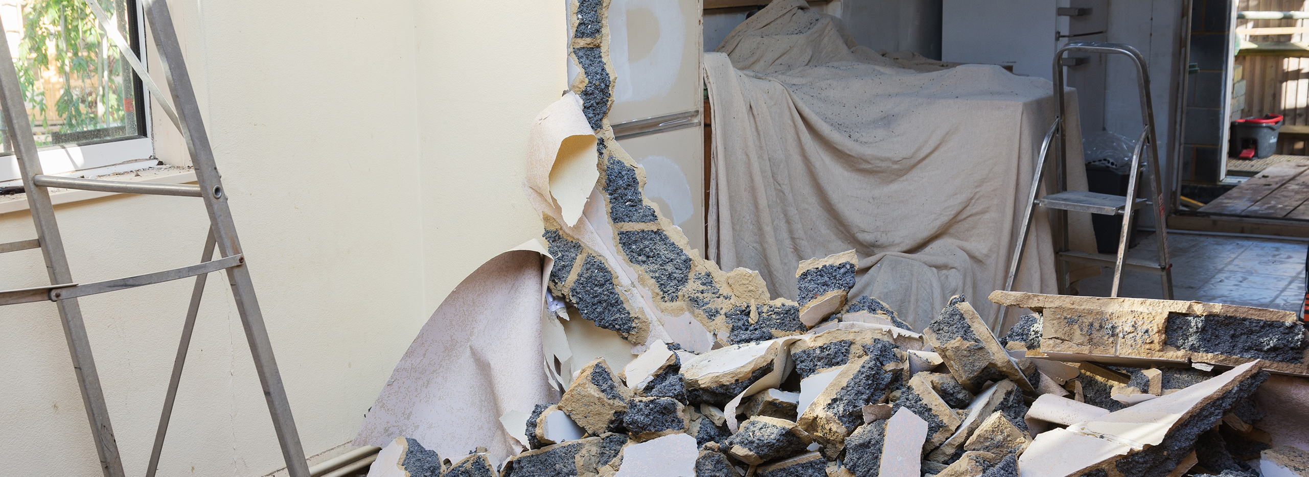 Zerbrochene Wandteile, Bauschutt und Leitern im Innenraum eines Hauses. Symbolbild für Pfusch am Bau.