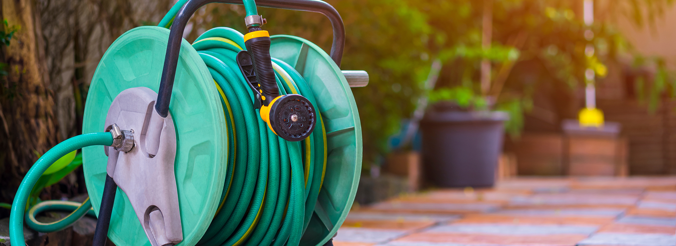 Grüner Gartenschlauch auf einer Schlauchtrommel aufgewickelt.