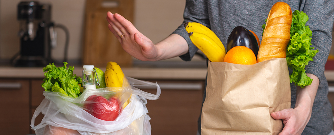 Person entscheidet sich in der Küche für eine nachhaltige Papiertüte mit frischen Lebensmitteln statt einer Plastiktüte.