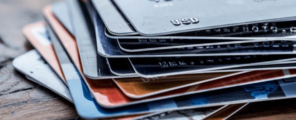 Nahaufnahme eines Stapels verschiedener Bank- und Kreditkarten auf einer Holzoberfläche. Symbolbild für nachhaltige Finanzprodukte, recycelte Bankkarten und umweltfreundliche Zahlungslösungen.
