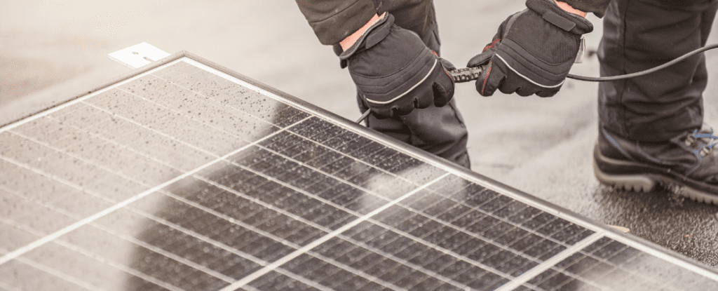 Handwerker mit schwarzen Handschuhen installiert eine Solaranlage. Symbolbild für erneuerbare Energien, Photovoltaik-Installation und nachhaltige Stromerzeugung.