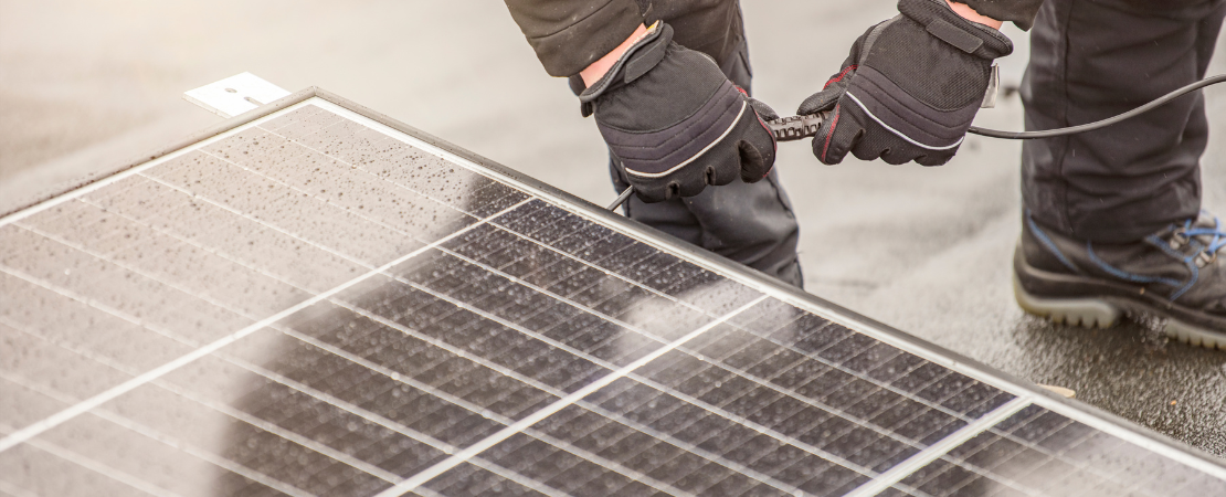 Handwerker mit schwarzen Handschuhen installiert eine Solaranlage. Symbolbild für erneuerbare Energien, Photovoltaik-Installation und nachhaltige Stromerzeugung.