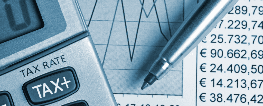 Taschenrechner mit 'TAX'-Anzeige, Finanzdiagramme, Euro-Zahlen und ein Stift auf einem Schreibtisch